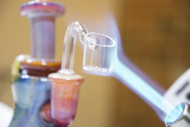 close up of a torch emitting a blue-ish fire onto the banger of a rig