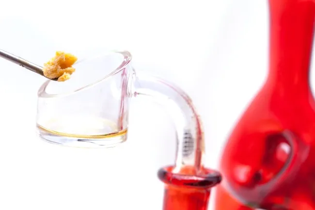 a chunk of wax being put into a banger with a titanium dab tool