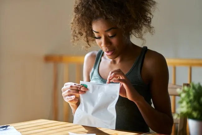 A black woman opening a cannabis child proof plastic bag.