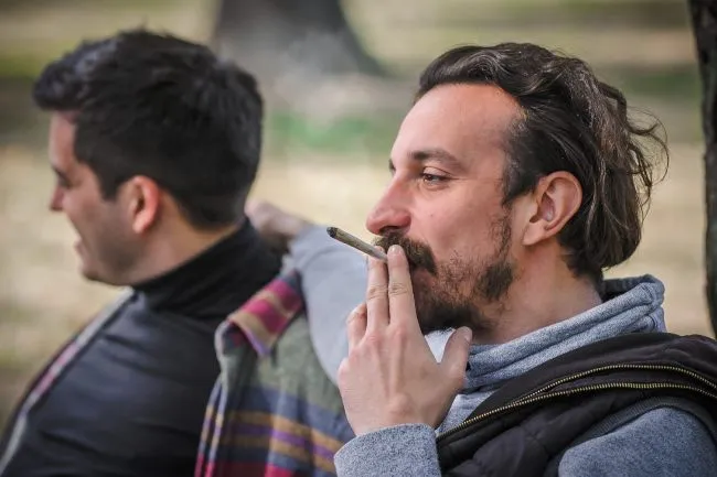 Two men smoking a cannabis joint in the park